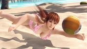 Woman in pink swimsuit playing with a beach ball on a sandy beach.