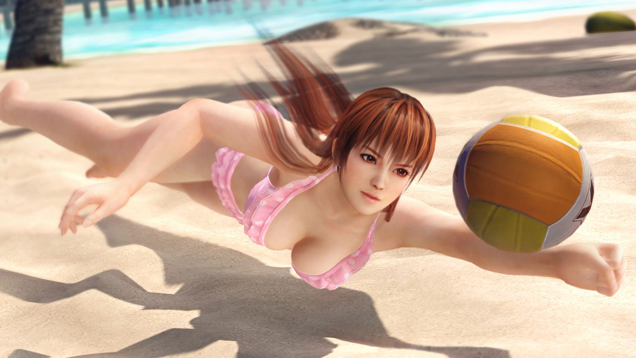 Woman in pink swimsuit playing with a beach ball on a sandy beach.