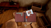 Brown leather wallet with money and card on a wooden floor with cardboard boxes