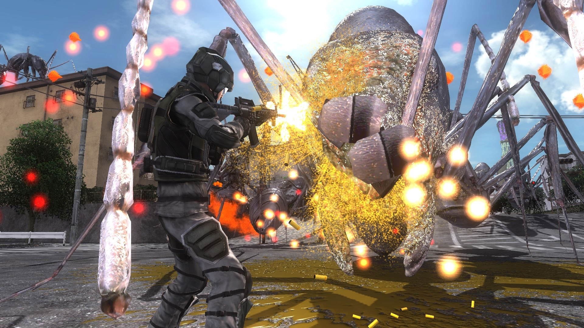A video game scene showing a soldier in dark tactical gear firing at a giant spider-like creature in an outdoor urban environment, with sparks and glowing effects visible.