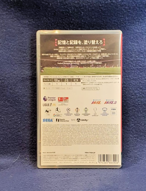 Back cover of a Japanese video game case for Football Manager 2024, photographed flat on a dark blue textured fabric background.