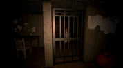A dark, eerie scene showing a barred metal door in a dimly lit room with peeling walls, a table and chair on the left, and a red pot on the right. A ghostly figure is faintly visible behind the bars.