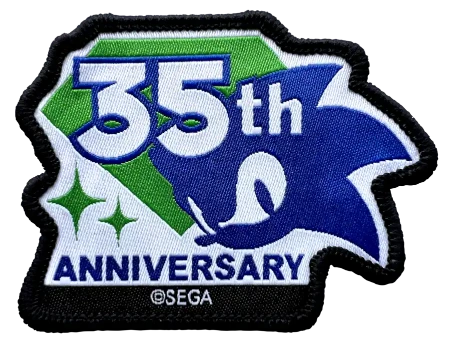 A 35th Anniversary embroidered patch featuring Sonic the Hedgehog artwork, with white '35th' text over green and blue sections, 'ANNIVERSARY' at the bottom, and a black stitched border. A small '©SEGA' mark is visible near the bottom edge.