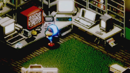 Pixel-art scene of a small blue character standing in a cluttered office or study with desks, computers, shelves, and a green floor.