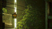 Vintage-style lamp hanging from a wire with greenery in the background