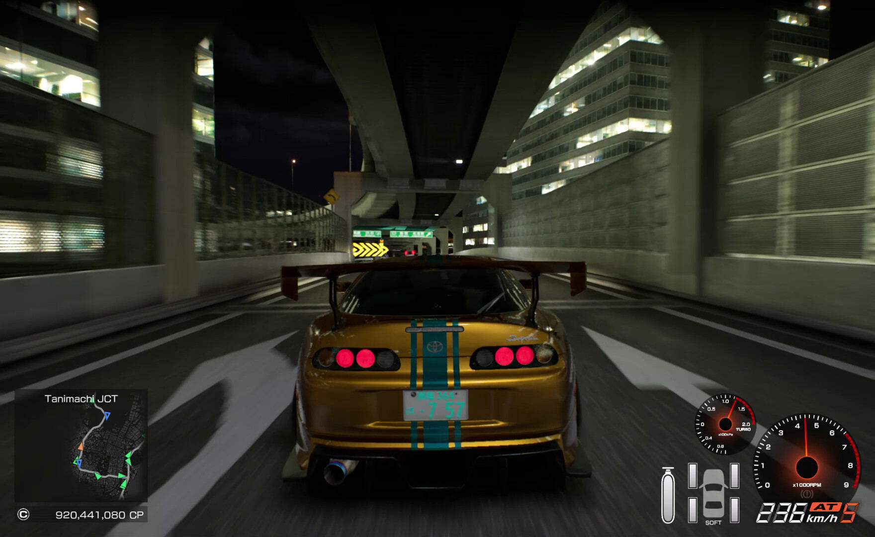 Gold sports car racing on a city street at night with tall buildings in the background.