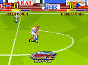 Soccer game in progress with two players on a virtual field, surrounded by colorful advertisements and branding.