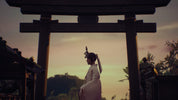 A woman in a white traditional Japanese outfit stands in profile beneath a large dark torii gate at sunset, with a softly glowing sky and outdoor setting in the background.